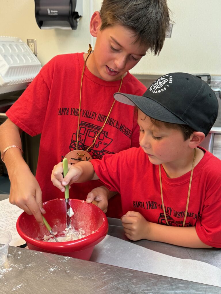 2 kids at Wild West Camp 2024 making homemade buttermilk biscuits