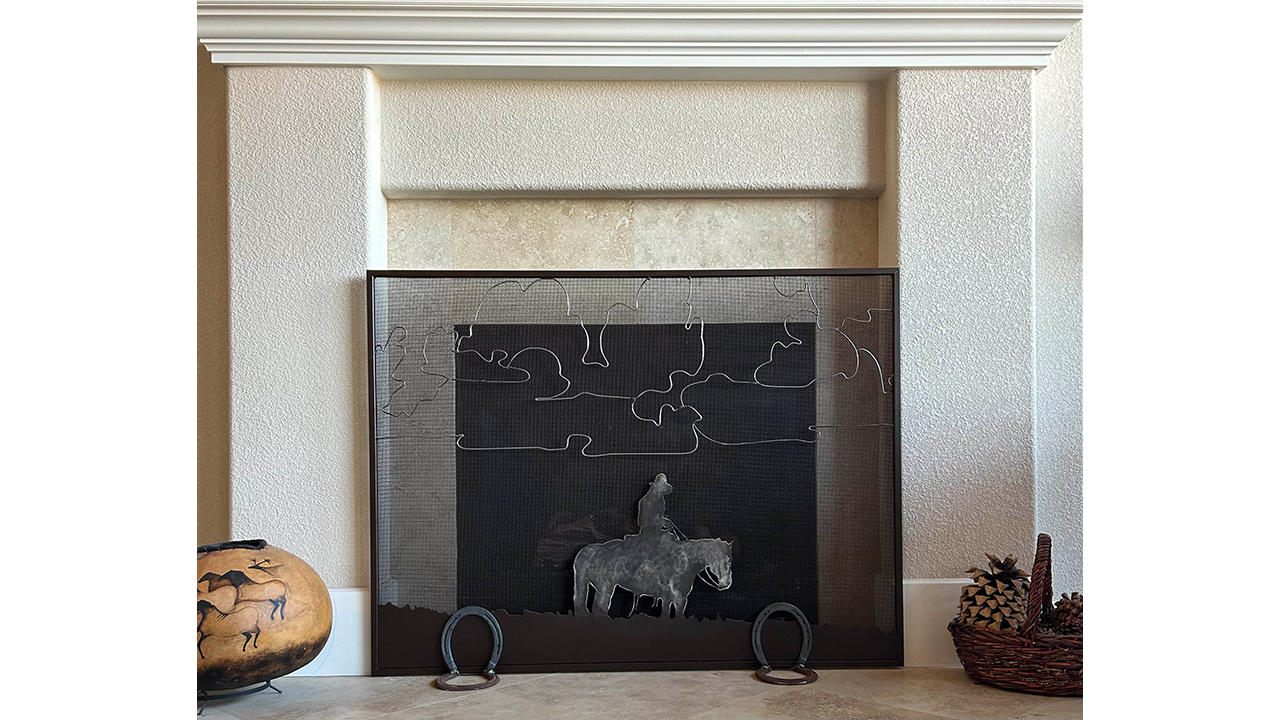 metal fireplace screen with horseshoe feet and horse & rider profile artwork